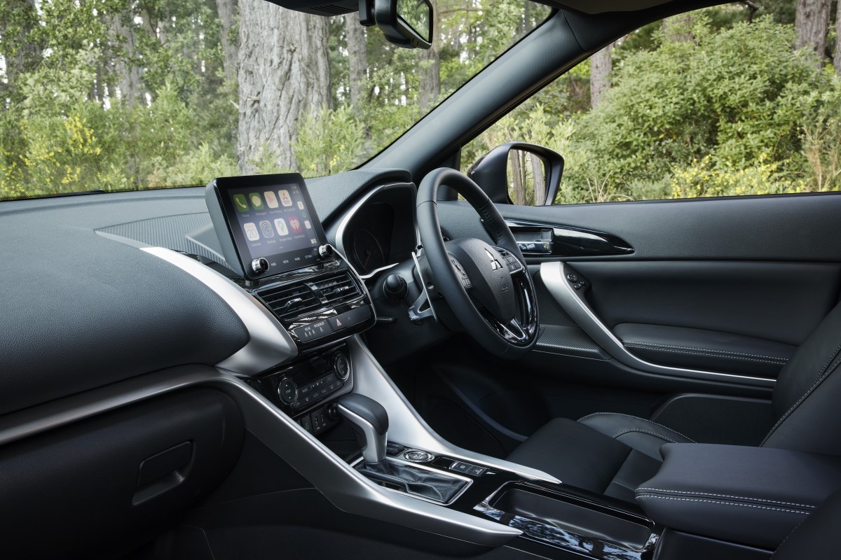 An interior shot of the Mitsubishi Eclipse Cross showing the driver's side, with a forest outside the window