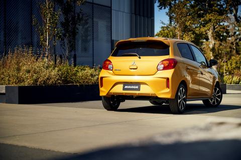 A full shot of the back of a yellow Mitsubishi Mirage from distance