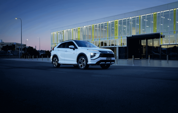 A Mitsubishi Eclipse Cross PHEV parked in front of a city building at night